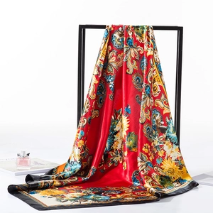 Detail of red Baroque silk scarf with gold patterns and magazine on white backdrop