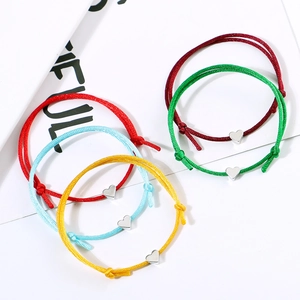 Macro shot of colorful woven bracelets with polished metallic heart pendants