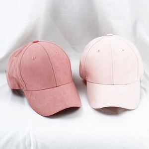 Pink faux suede baseball caps in rose and peach tones on white textured background