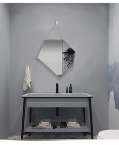 Close-up of golden geometric wall mirror with chain hanging in a modern bathroom