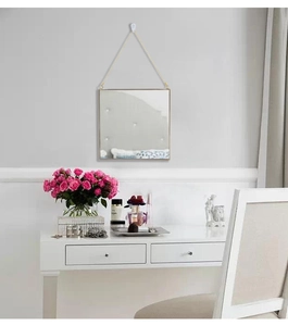 Detail of square gold metal frame wall mirror with hanging chain for modern home decor
