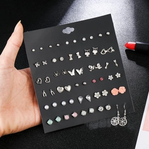 Detail of earring set featuring crystal heart, bow, and owl charms on black card display