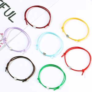 Detail view of seven colorful braided heart charm bracelets with adjustable sliding knots