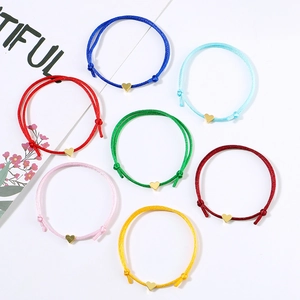 Detail of seven colorful woven lucky heart bracelets with adjustable gold charms
