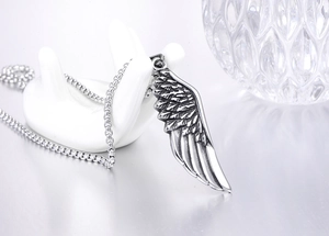 Detailed close-up of a vintage steel feather pendant on a white hand display stand