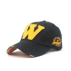 Close-up of black baseball cap with yellow W patch embroidery and distressed brim edge