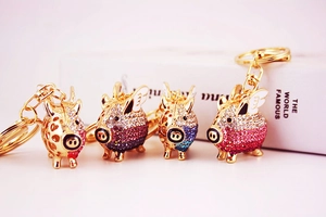 Detailed view of flying pig keychains with sparkling gradient rhinestones and golden wings