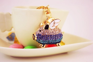 Macro detail of flying pig keychain with pink-blue gradient rhinestones and white wings