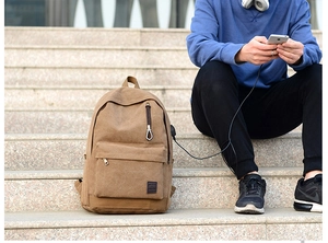 Zaino in tela marrone con porta USB esterna mostrato in uso esterno su scale di marmo