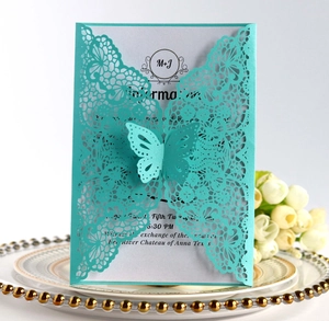 Detail of laser-cut turquoise butterfly wedding invitation card with elegant lace texture