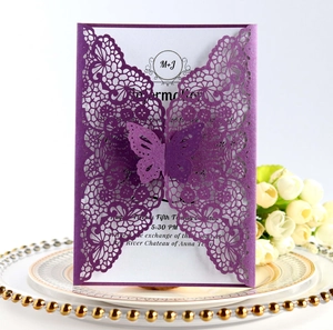 Detail of laser-cut butterfly invitation on gold-rimmed plate with white flowers