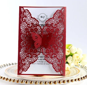 Close-up of a laser-cut red lace wedding invitation with a 3D butterfly on a gold plate