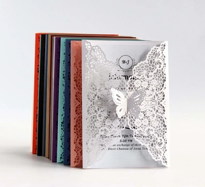 Macro detail of laser cut butterfly lace wedding invitations in various elegant colors
