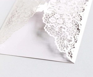 Macro view of white paper envelope featuring intricate laser-cut floral lace details