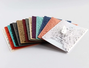 Macro detail of laser-cut butterfly lace wedding invitations in various vibrant colors