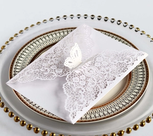 Close-up of laser-cut white envelope with intricate butterfly and floral patterns