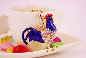Macro shot of blue enamel rooster keychain with crystal rhinestones and gold hardware