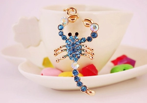 Macro detail of scorpion keychain pendant with blue rhinestones and gold alloy plating