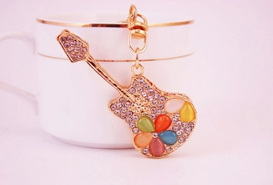 Close-up of golden metal guitar keychain with colorful opals and sparkling rhinestones