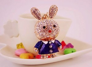 Close-up of golden bunny keychain with rhinestones and blue enamel dress details