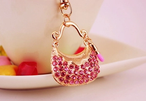 Macro shot of gold metal handbag keychain with pink rhinestones and lipstick charm