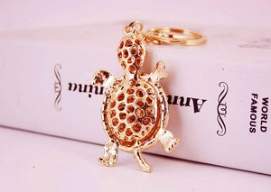 Detailed close-up of a golden metal turtle keychain with a hollow mesh pattern design