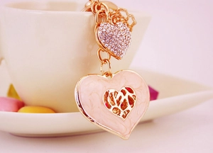 Close-up of pink enamel heart keychain with sparkling rhinestone charm and gold finish