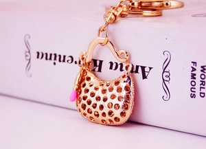 Close-up of a gold handbag keychain with pink lipstick charm and hollow dot design