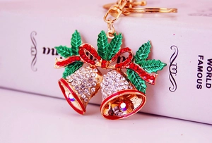Close-up of rhinestone Christmas bell keychain with red bow and green enamel leaves