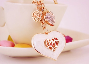 Detail of gold keychain with white heart pendant, rose charm, and rhinestone heart