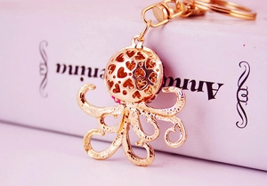 Close-up of golden octopus keychain featuring pink rhinestones and heart cutouts