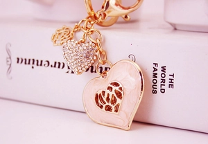 Macro shot of gold heart keychain with pink enamel, floral charm and sparkling rhinestones