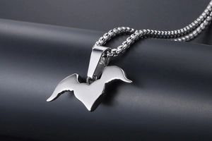 Macro detail of silver stainless steel heart wing pendant with a polished box chain