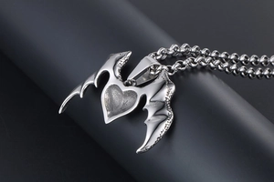 Detail of silver titanium steel heart pendant with intricate wings on a sturdy chain