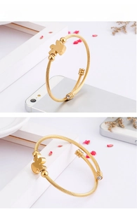 Detail view of gold titanium steel twisted cable bangle featuring a teddy bear charm and zircons
