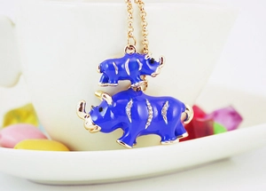 Close-up of blue enamel rhino charms with gold trim and rhinestones on a metal chain