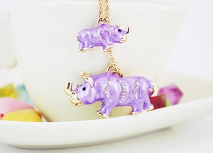 Detailed close-up of purple enamel rhino pendants with rhinestones on a gold chain