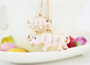 Detailed close-up of a golden keychain featuring pink enamel mother and baby rhinos with rhinestones
