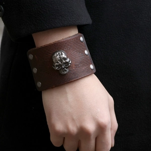 Men's wide brown leather bracelet featuring a metal skull emblem and silver rivets
