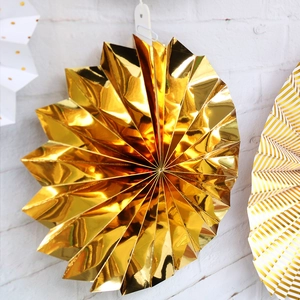 Detailed macro view of a metallic gold folding paper fan for festive party decoration