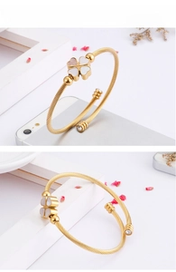 Close-up of golden clover bangle with white shell inlay and twisted metal texture