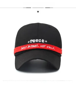 Detail of black cotton baseball cap featuring red strap with white letter embroidery