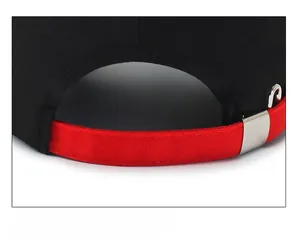 Detail of black cotton baseball cap showing adjustable red strap and silver buckle