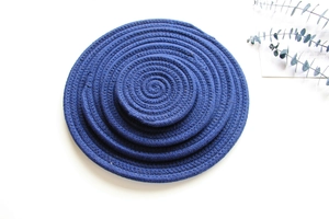 Top view of navy blue woven cotton rope coasters in multiple sizes on white background