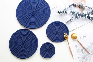 Macro detail of dark blue braided cotton coasters in a minimalist Nordic table setting