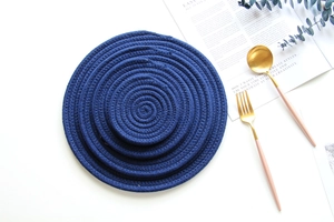 Macro detail of blue woven cotton rope coasters with gold cutlery and eucalyptus leaves