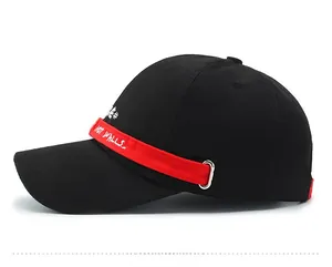 Detail of black cotton baseball cap featuring a red ribbon with NOT WALLS text and embroidery