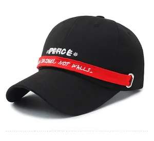 Detail of black cotton cap featuring #PEACE# embroidery and red decorative strap