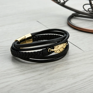 Close-up of black layered leather bracelet with golden feather pendant and magnetic clasp