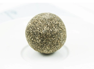 Macro view of a natural compressed catnip ball for dental cleaning on a white plate